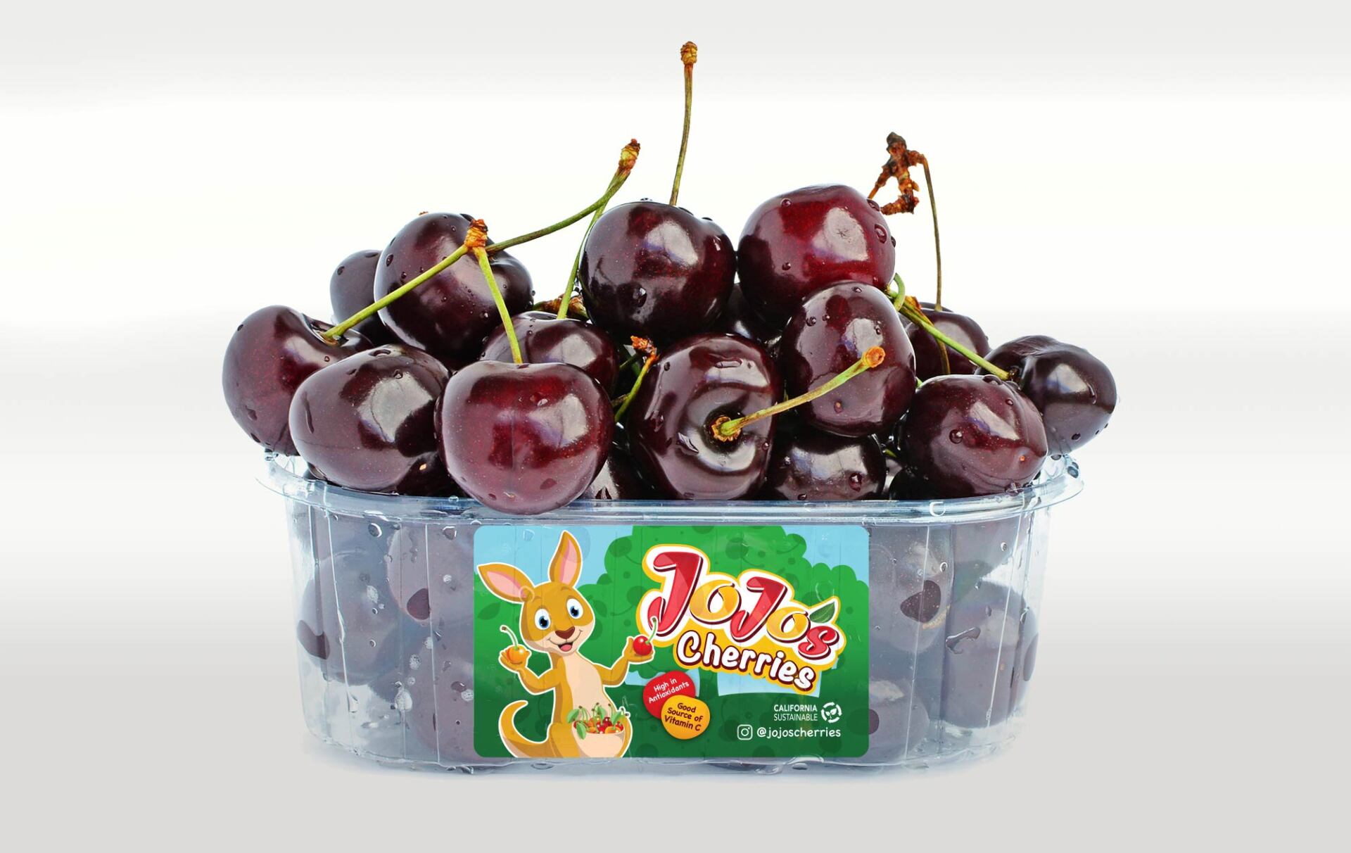 A plastic container full of cherries labeled JoJo Cherries