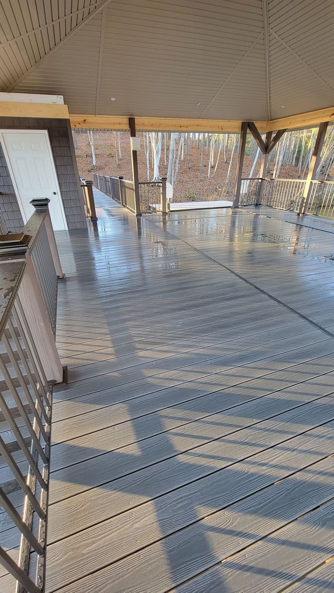 A wooden deck with a view of a lake and a tree.
