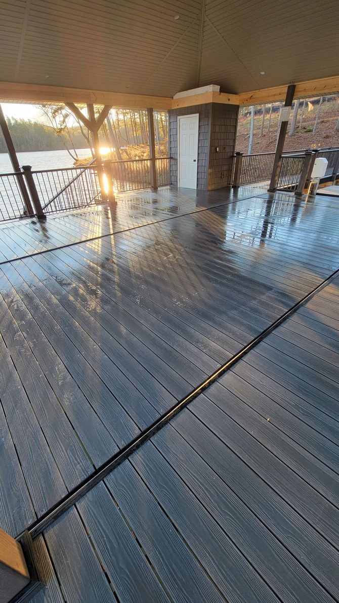 A wooden deck with a view of a lake and a tree.