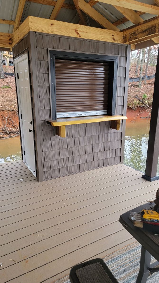 A wooden deck with a shed and a window on the side of it.
