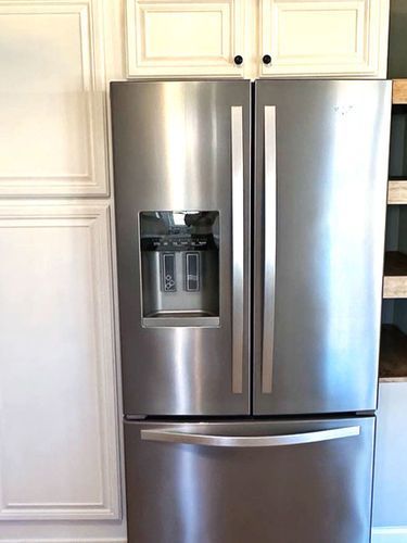 A stainless steel refrigerator with a water dispenser is sitting in a kitchen.