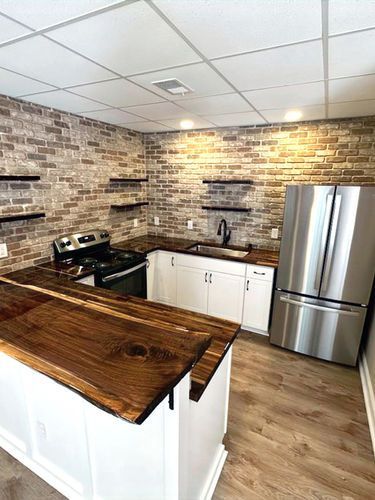 A kitchen with a stove , refrigerator , sink and wooden counter tops.