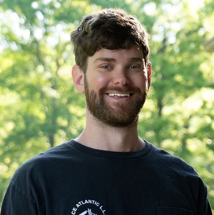 A man with a beard wearing a black shirt that says peace atlantic