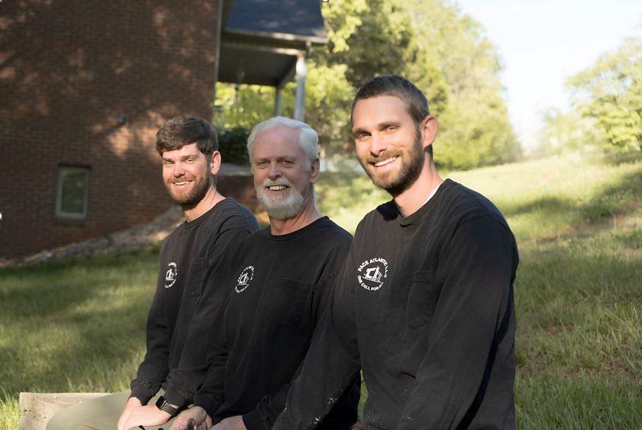 Three men are standing next to each other in a grassy field.