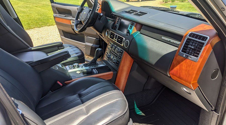 Interior of a luxury Range Rover with black leather seats, wood trim, and a center console.