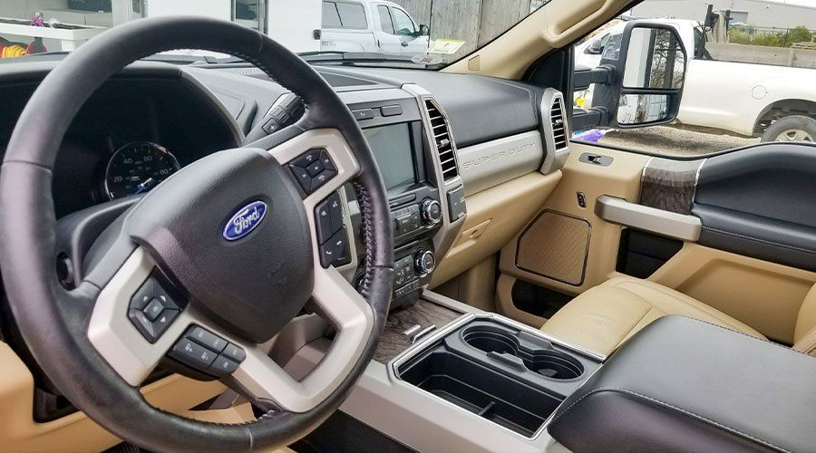 Tan Ford truck interior with steering wheel, dashboard, and center console visible.