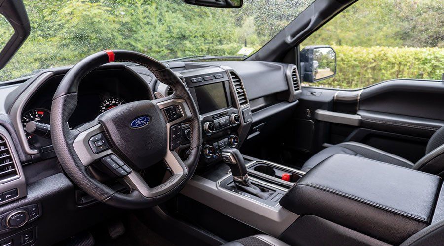 Interior view of a Ford truck, showing the dashboard, steering wheel, console, and passenger seat.