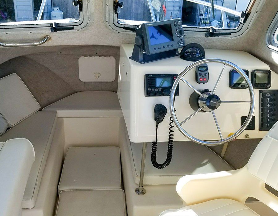 Boat cabin interior with steering wheel, navigation equipment, and seating.