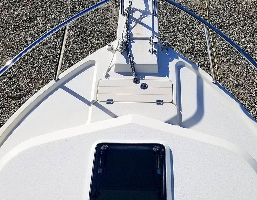 White boat bow with anchor chain, handrail, and access hatch.