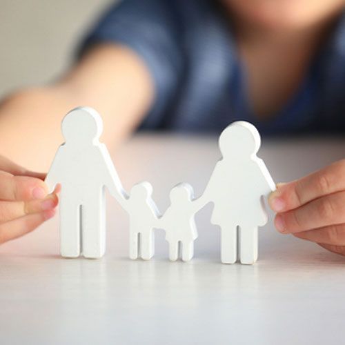 A person is holding a paper cut out of a family.