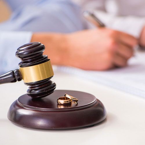 A couple of wedding rings sitting on top of a wooden gavel.