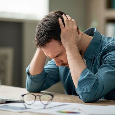 A man is sitting at a desk with his head in his hands.