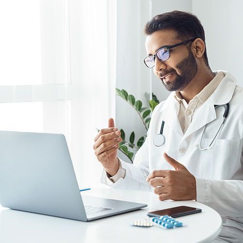 A doctor is sitting at a table using a laptop computer.