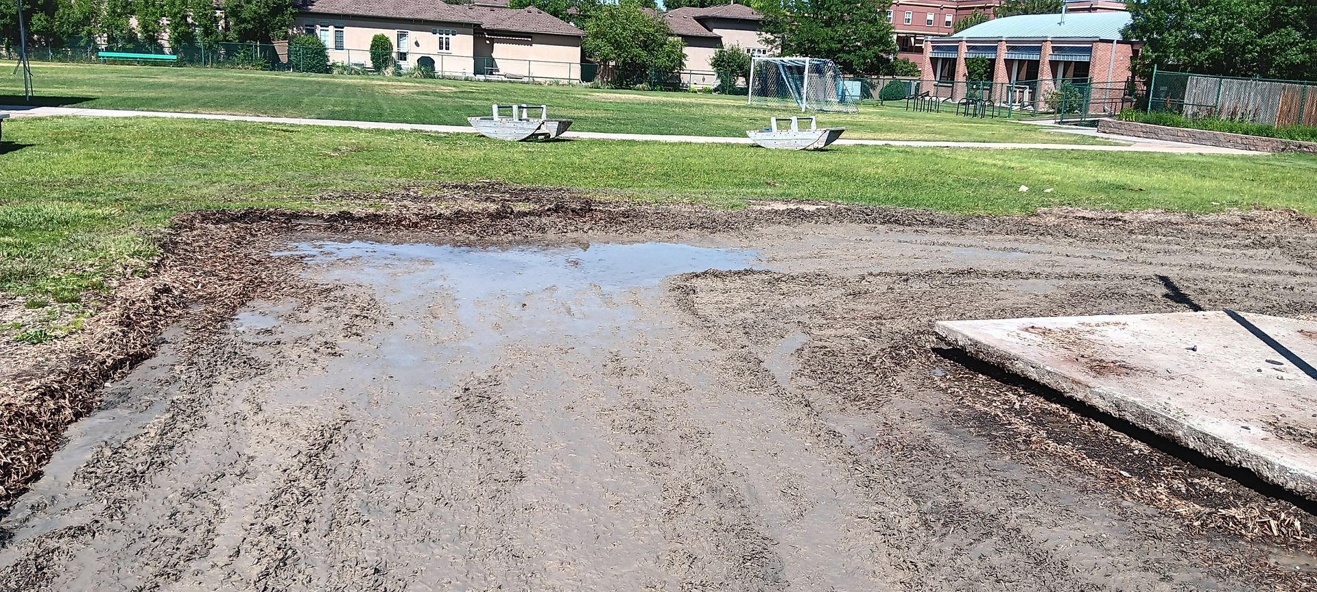 A muddy field with a puddle in the middle of it.