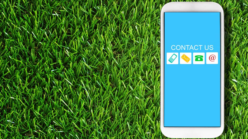 A cell phone is sitting on top of a lush green field of grass.