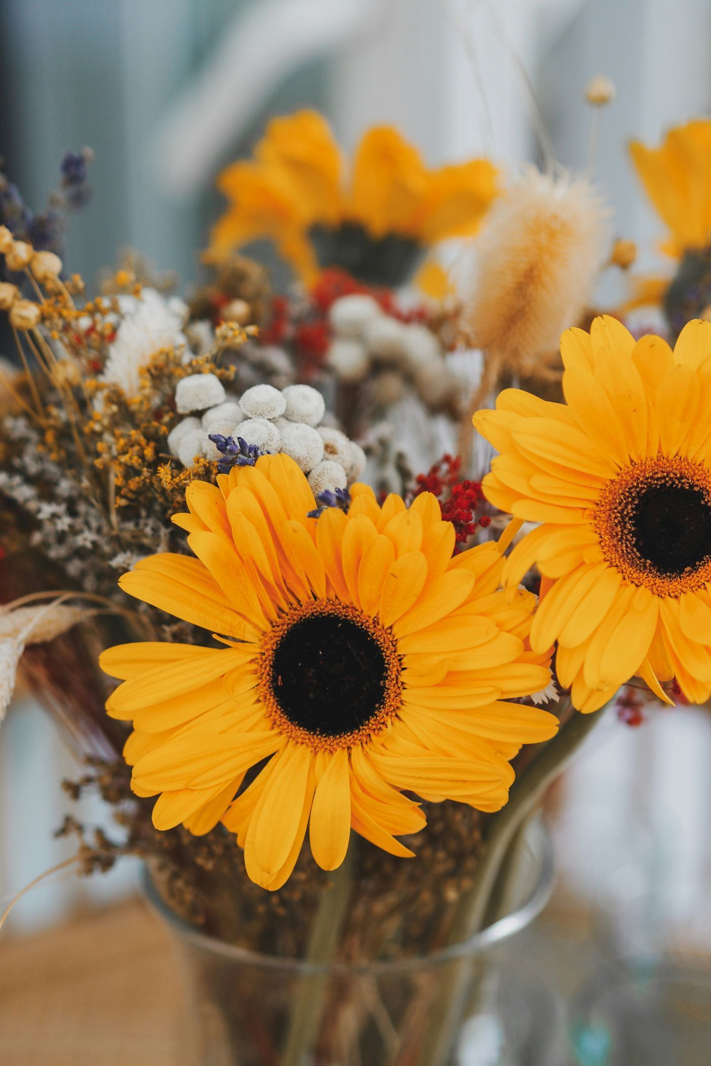 A close up of a vase filled with yellow flowers