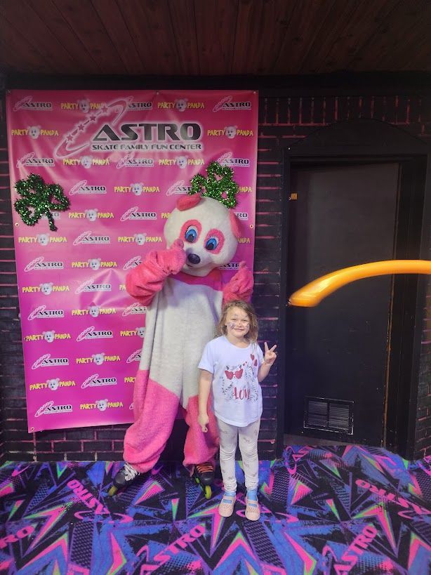 Girl poses with pink panda mascot at Astro Skate, showing peace sign.