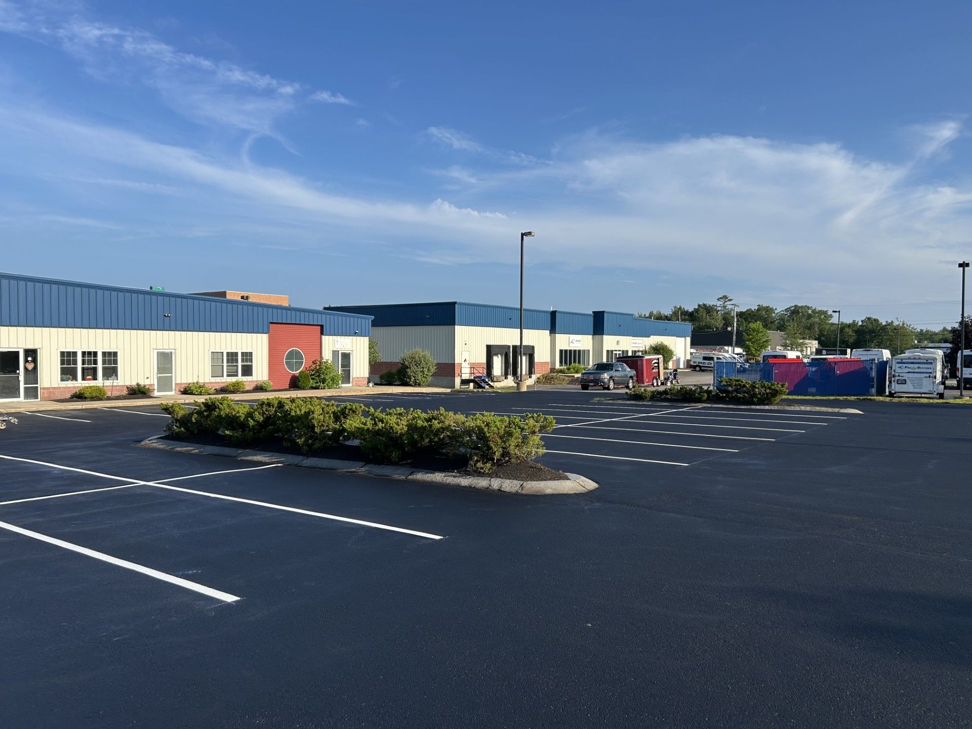 Exterior view of a building with a blue roof and tan walls, with a parking lot in front.