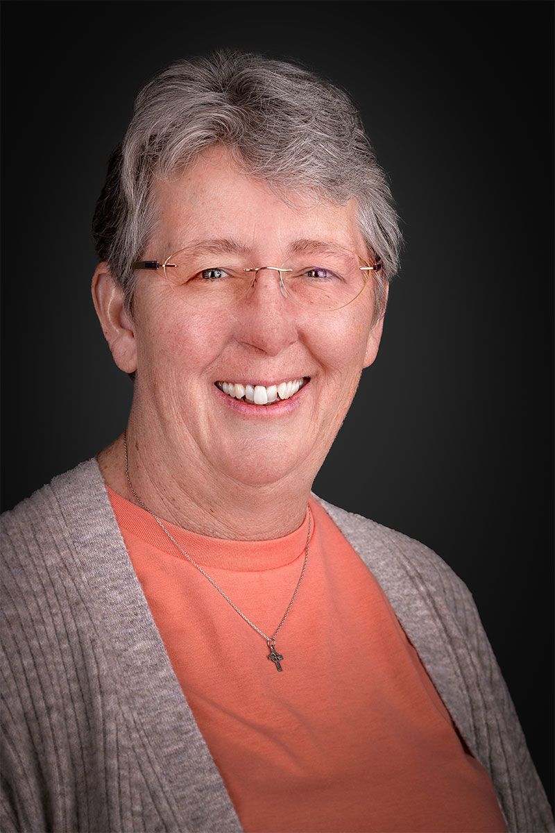Woman in clerical collar and cardigan smiles at the camera.