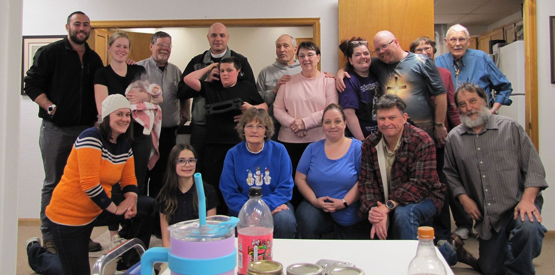 A large group of people smiling and posing for a group photo indoors in a brightly lit room.