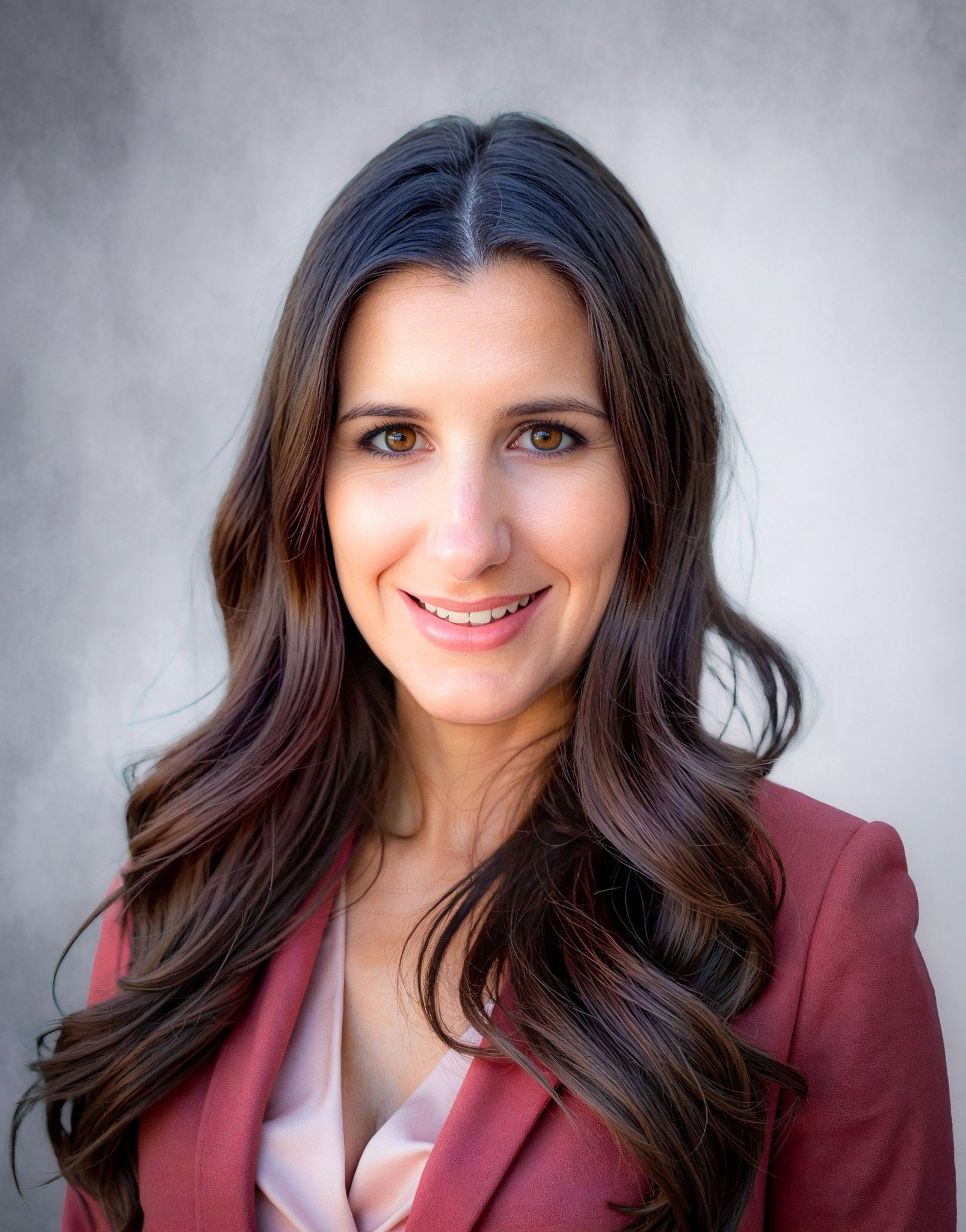 A woman with long hair is wearing a red jacket and smiling for the camera.