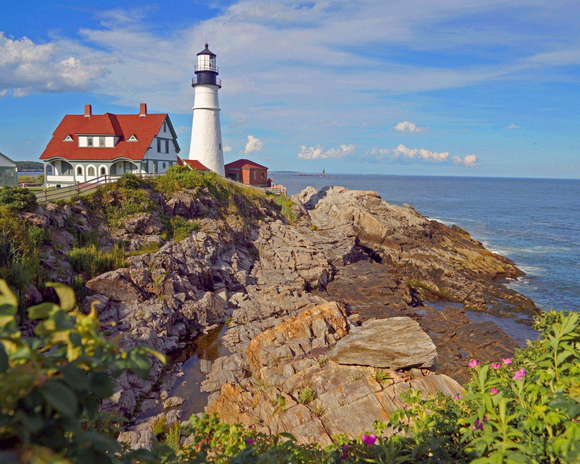 A lighthouse sits on top of a rocky cliff overlooking the ocean.