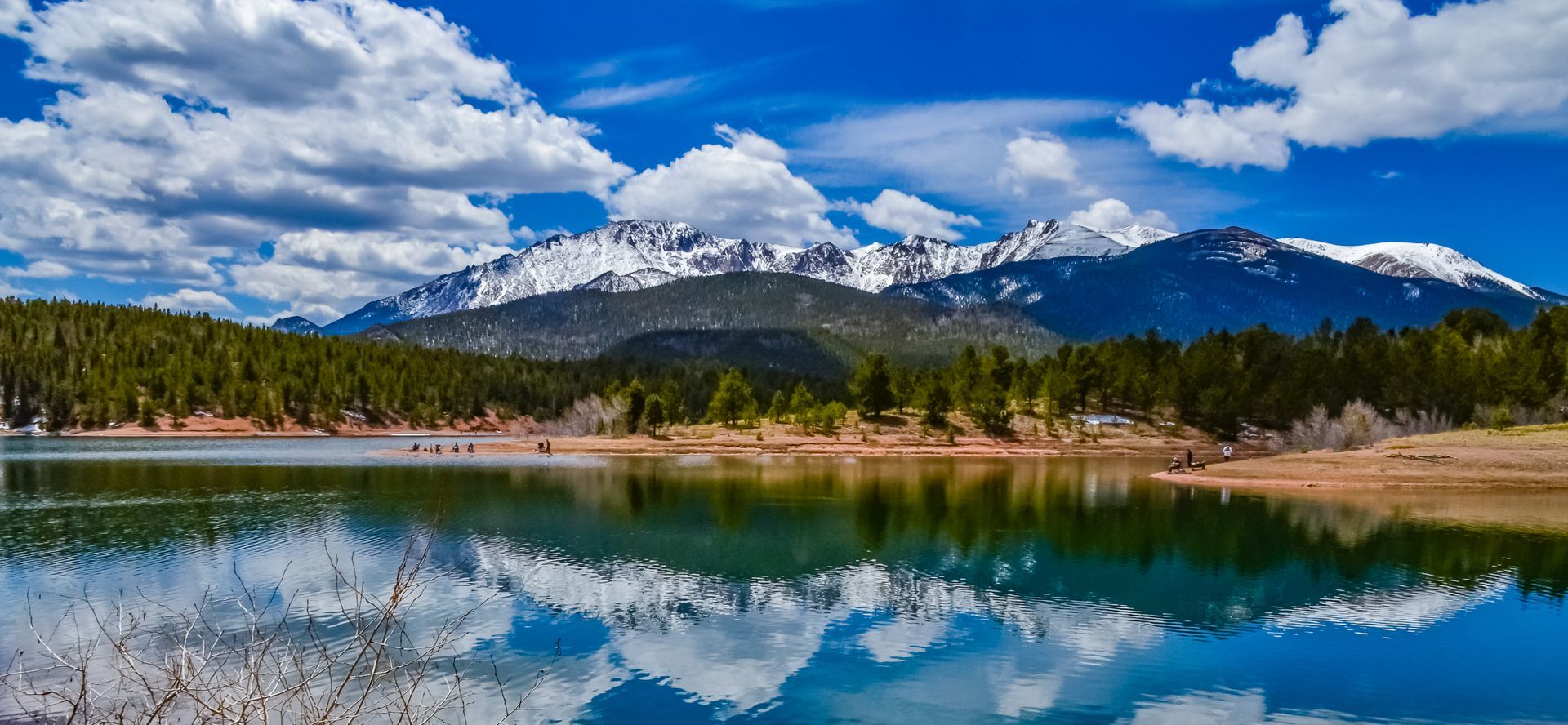 A lake with mountains in the background and trees on the shore.