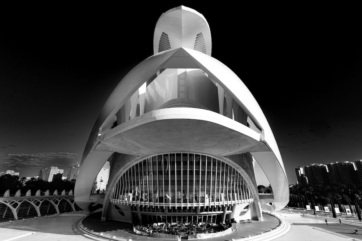 Black-and-white photo of a futuristic spiral building with a glass facade and arched concrete exterior.