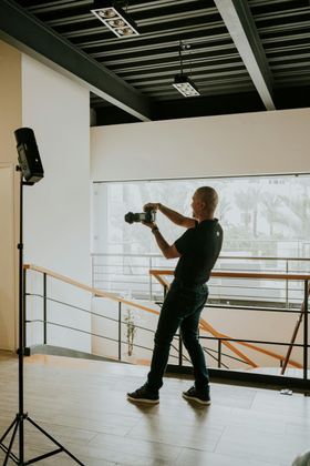 Man in an orange sweater photographing in a bright, modern lobby