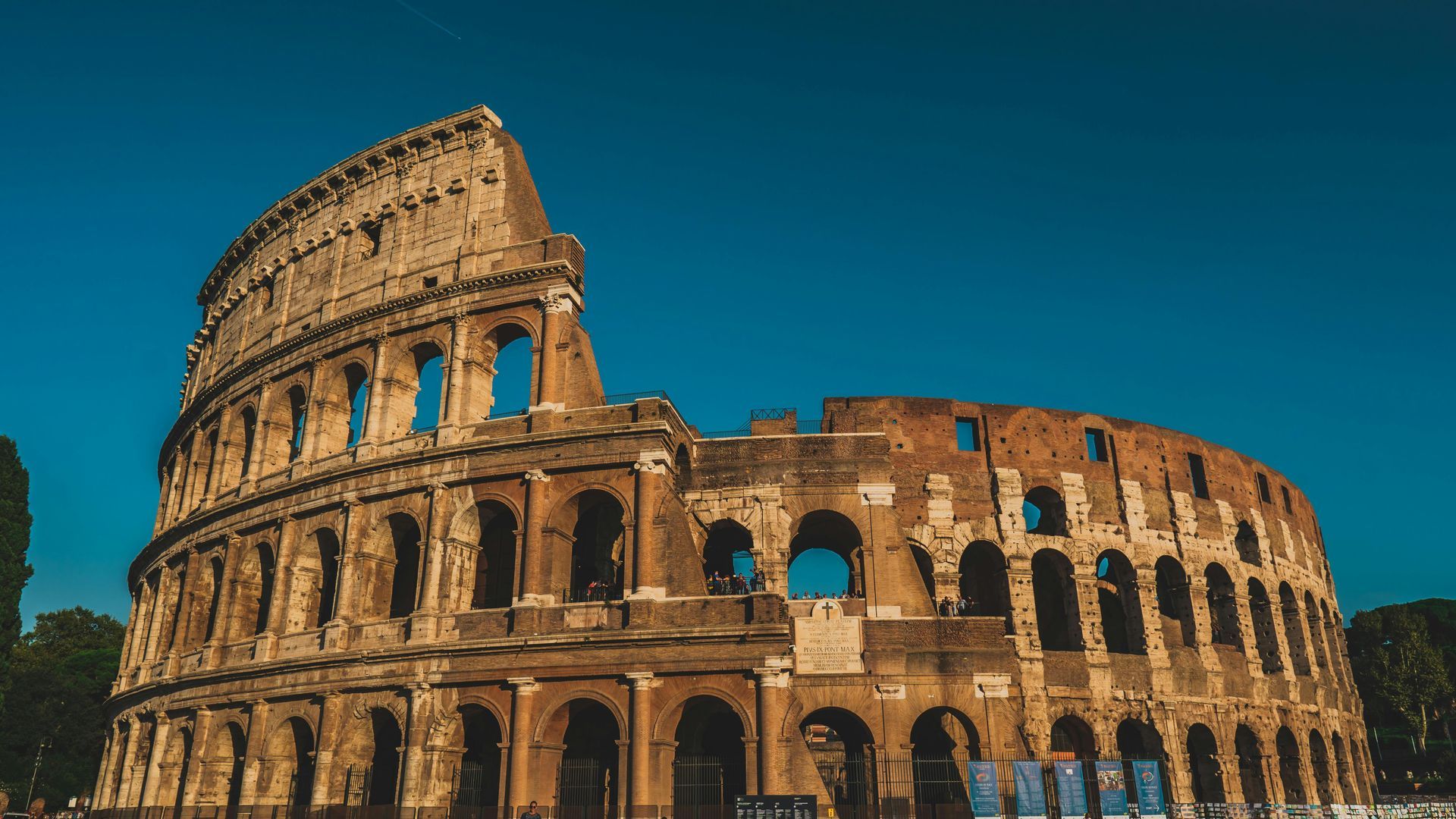 Colosseum in Rome, Italy, viewed from a low angle under a clear, blue sky.