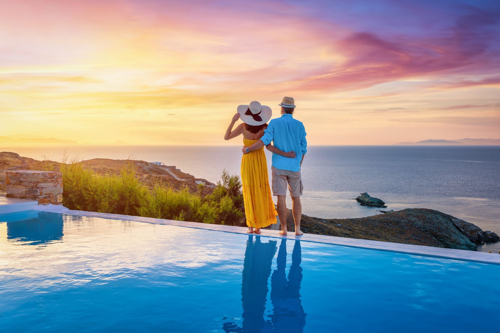 Couple overlooking ocean from infinity pool at sunset.