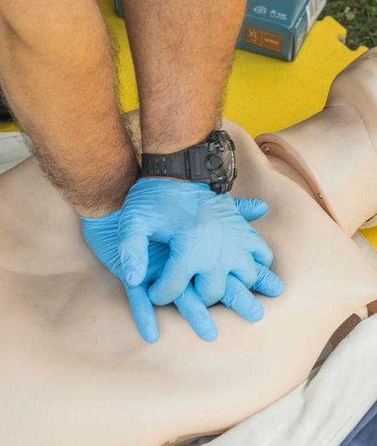 A man wearing blue gloves is performing a heart massage on a mannequin