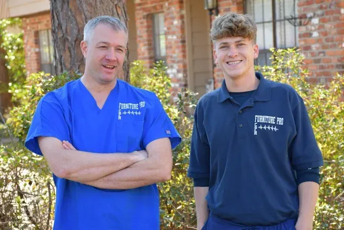 A man and a boy are standing next to each other in front of a brick building.
