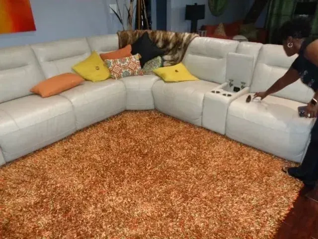 A woman is cleaning a sectional couch in a living room