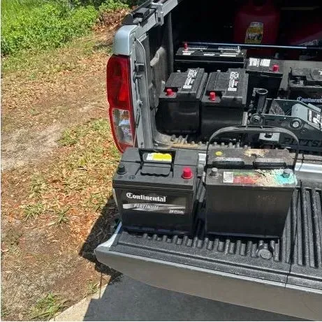Truck bed with multiple car batteries ready for disposal.
