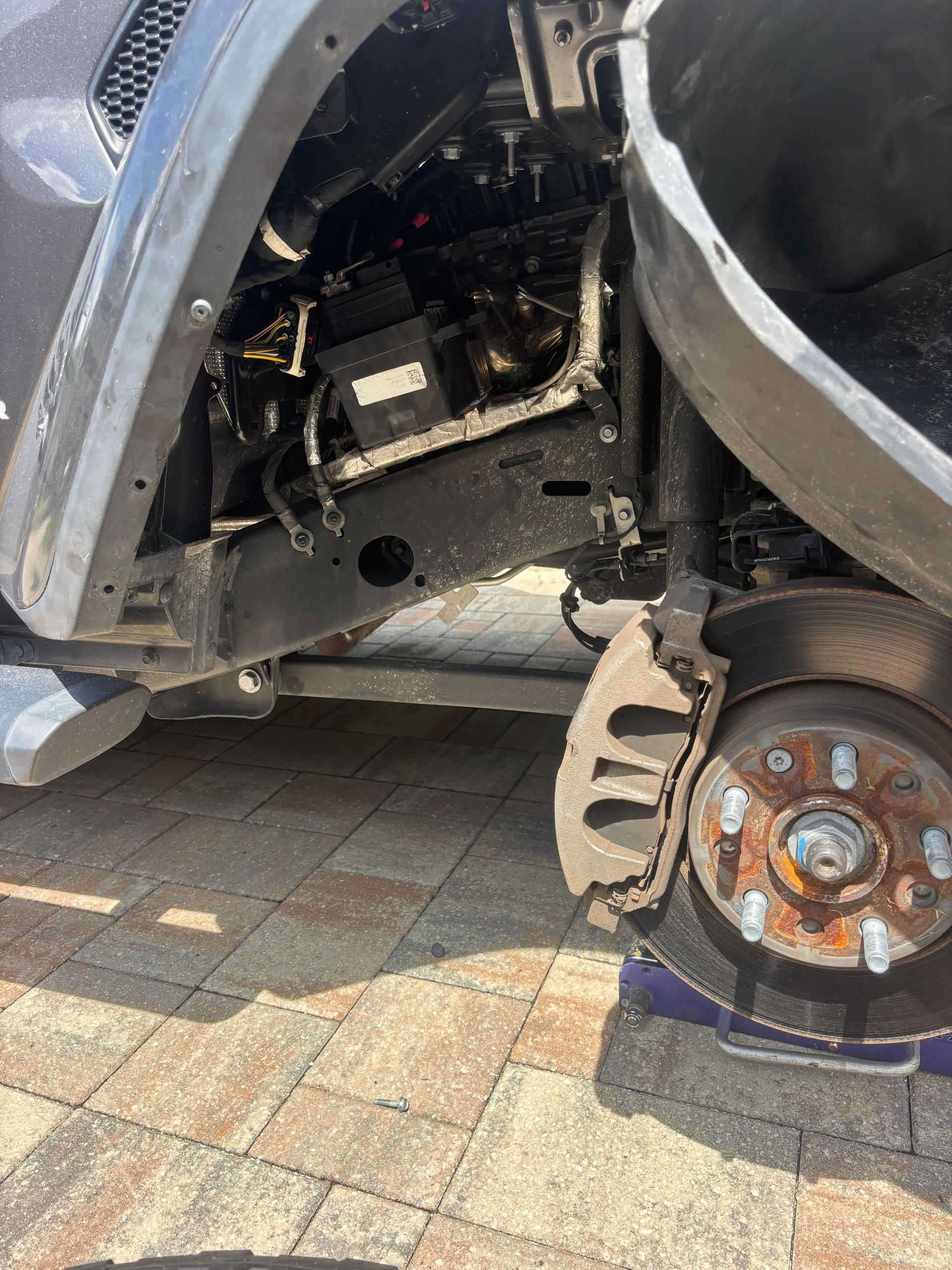 A car with front wheel removed, revealing suspension and brake parts.