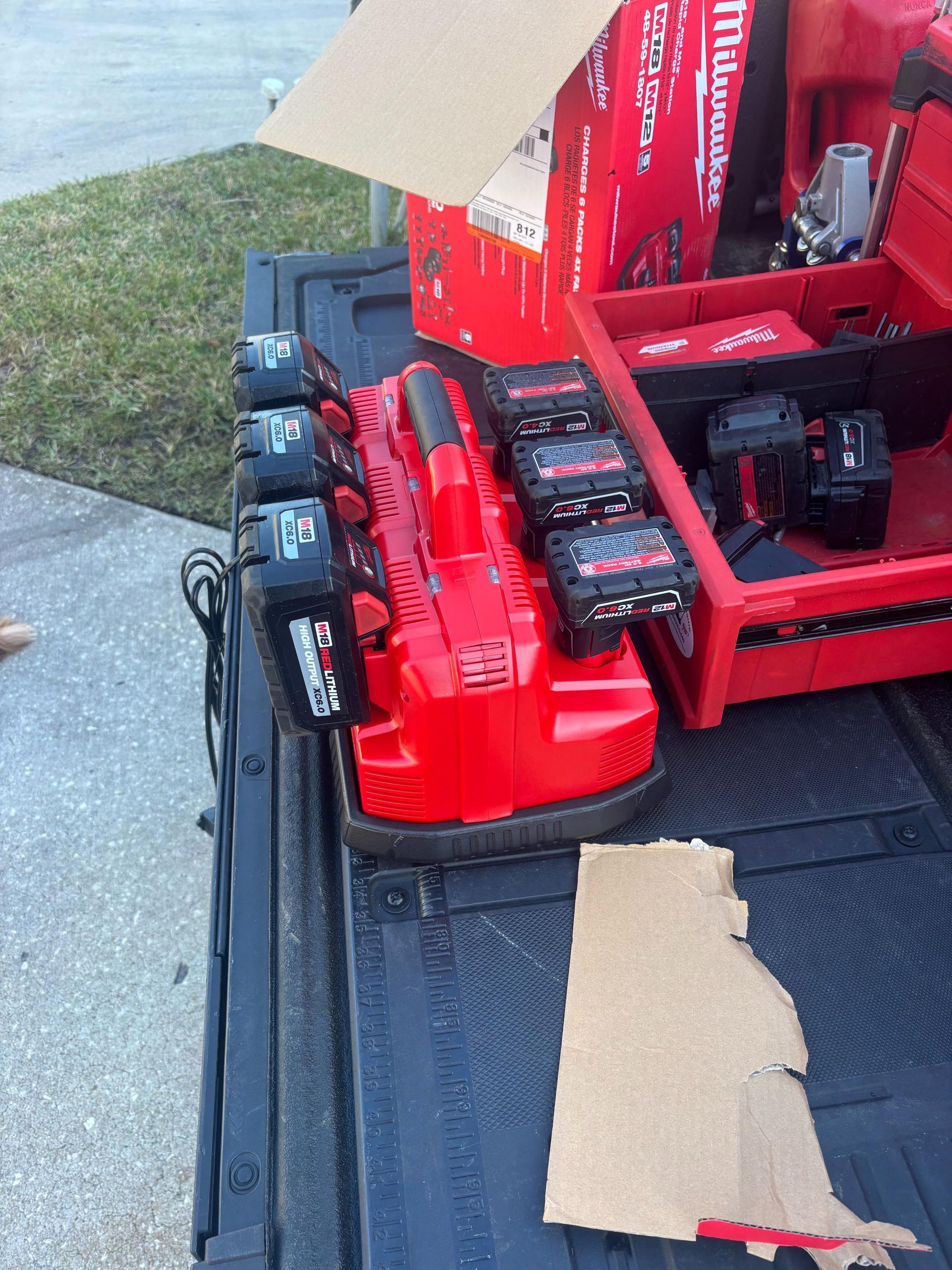 Red Milwaukee battery charger with multiple batteries in a truck bed.