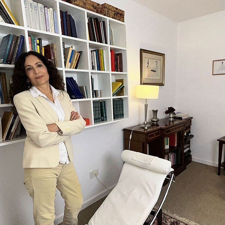 Una mujer está parada frente a una estantería con los brazos cruzados.