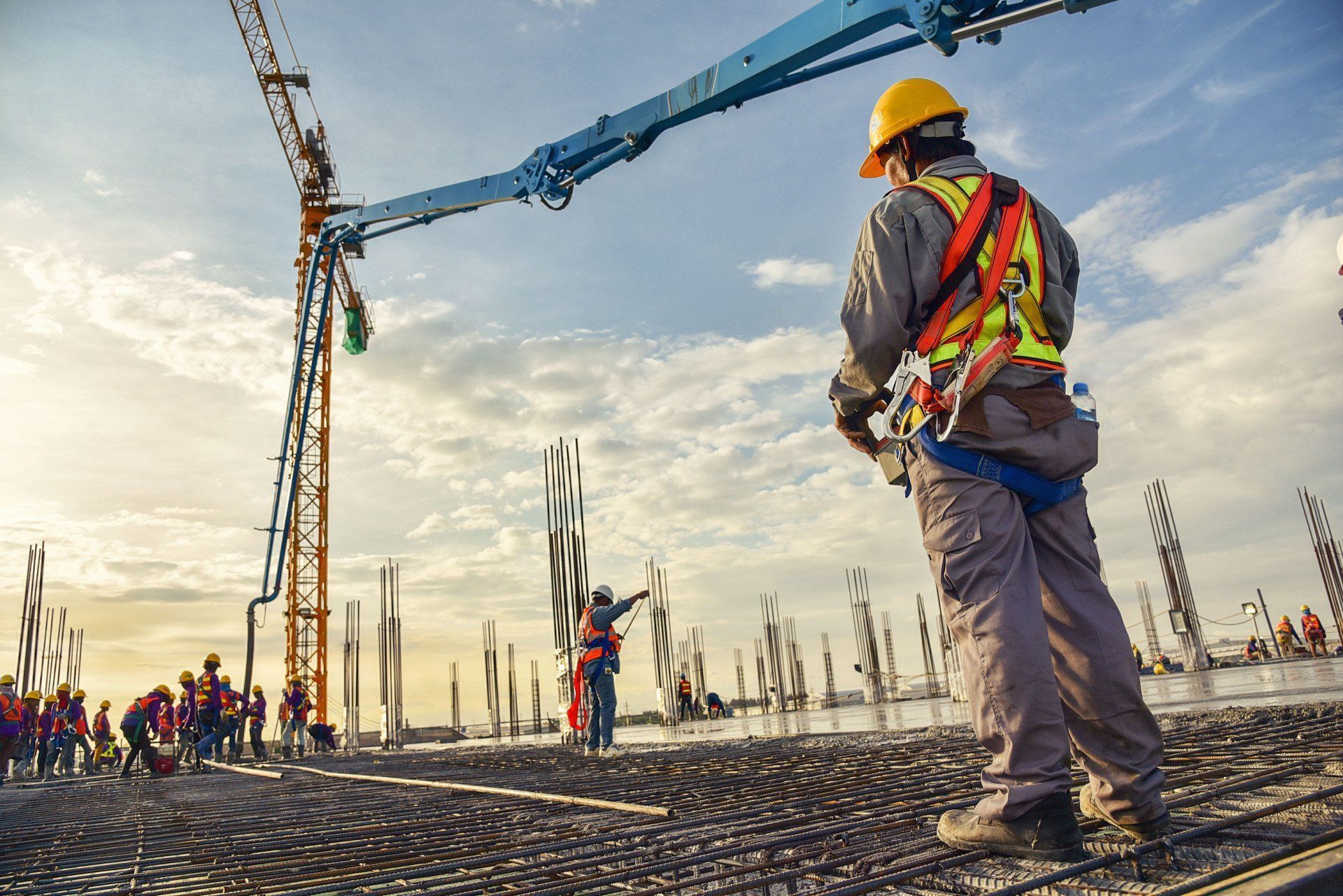 A construction worker is standing in front of a crane at a construction site