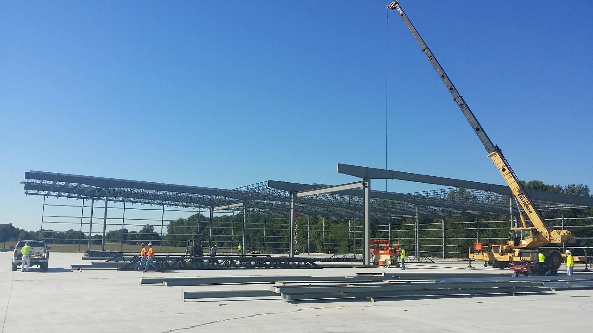 A crane is lifting a metal structure on a construction site