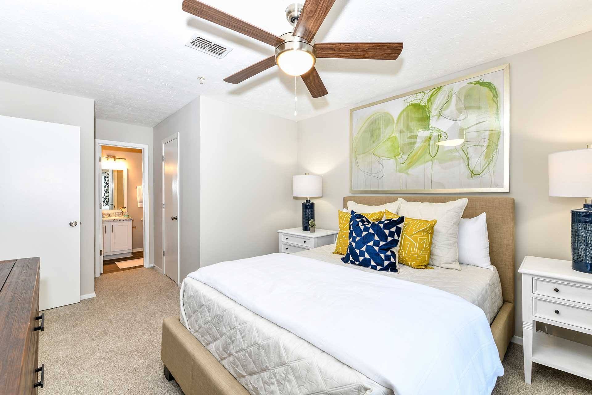 A bedroom with a large bed and a ceiling fan.
