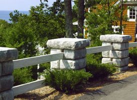 A stone fence with a house in the background