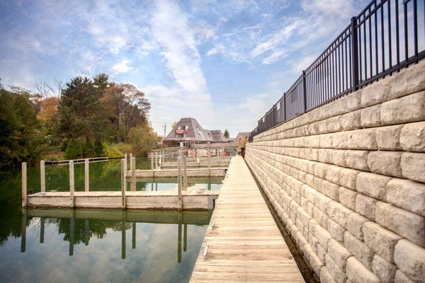 A dock with a fence and a brick wall next to a body of water.