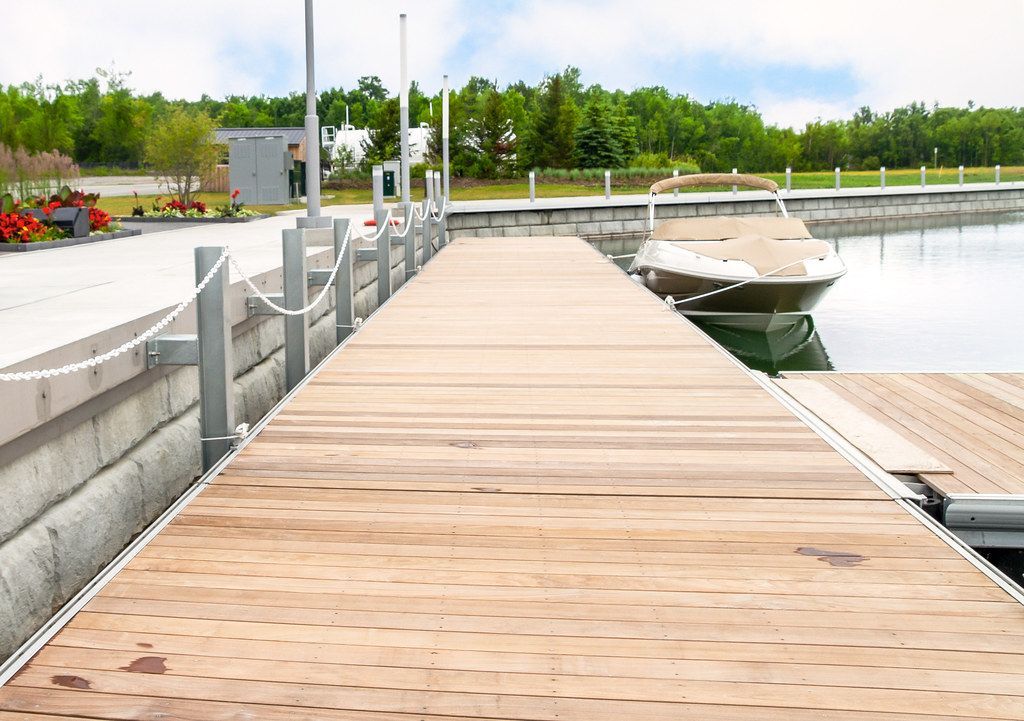 A boat is docked at the end of a wooden dock.