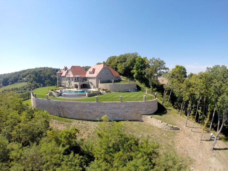 An aerial view of a large house on top of a hill surrounded by trees.