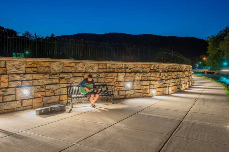 A man is sitting on a bench playing a guitar at night.