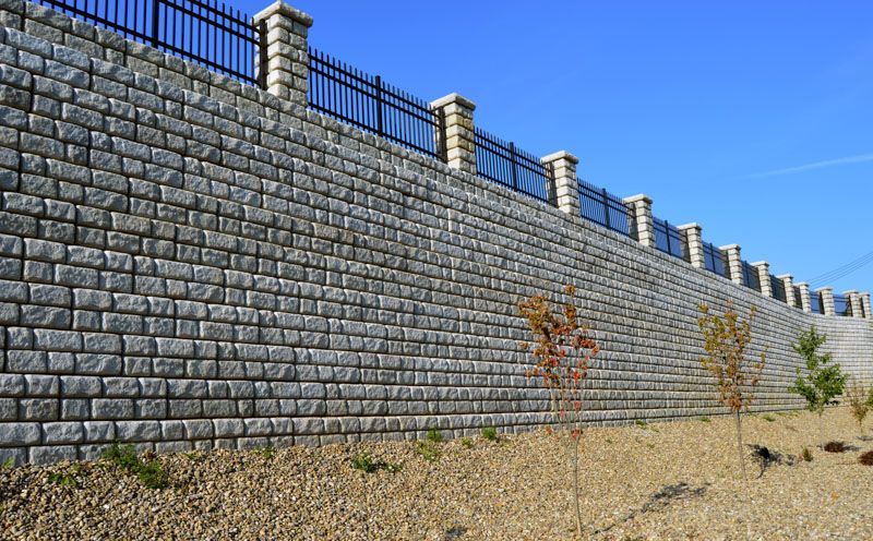 A large brick wall with a fence surrounding it.