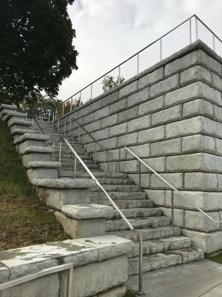 A set of stairs leading up to a stone wall with a railing.