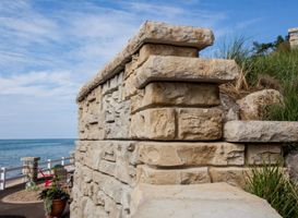 A stone wall with a view of the ocean in the background.