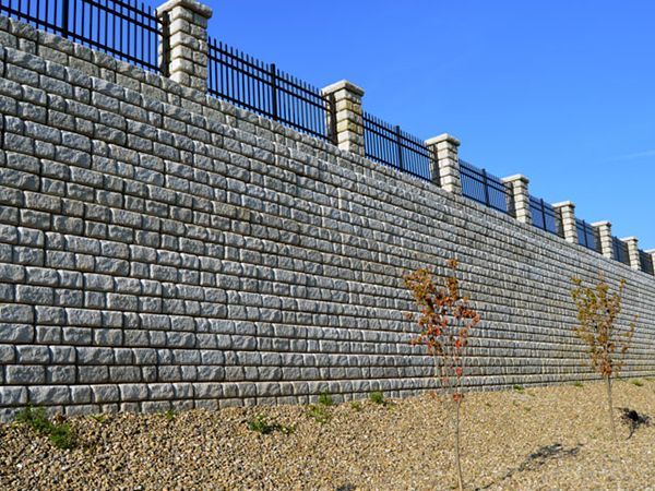 A large brick wall with a metal fence surrounding it.